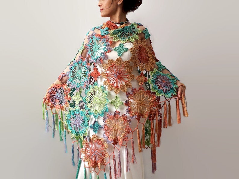 May include: A colorful crochet shawl with a floral design and fringe. The shawl is made with a variety of colors, including green, blue, orange, and pink.