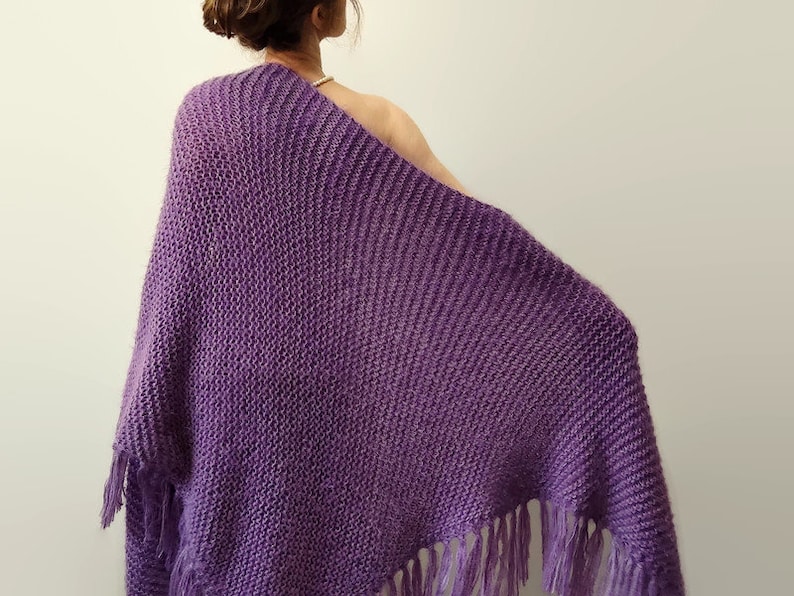 May include: A purple knitted shawl with fringe on the bottom edge.