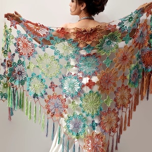 Peut inclure: Un châle en crochet coloré avec une bordure frangée. Le châle est réalisé avec une variété de couleurs, notamment le vert, le bleu, l'orange et le violet. Le châle est crocheté dans un motif délicat de fleurs.