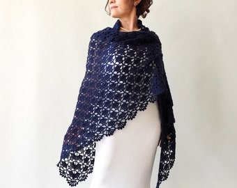May include: A navy blue crochet shawl with a delicate lace pattern. The shawl is draped over a white dress.