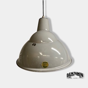 May include: A light grey industrial pendant light with a dome-shaped metal shade. The fixture features a black cord and a small circular label on the front that reads Benjamin Electric Limited. There is a minor dark chip in the enamel finish.
