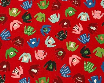 Puede incluir: Tela roja con un patrón repetido de jerséis navideños coloridos. Los jerséis presentan varios diseños, incluyendo copos de nieve, bastones de caramelo, renos y las palabras "fa la la la".