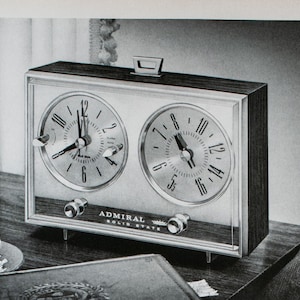 May include: A vintage advertisement for Admiral solid-state clock radios. The ad features a close-up of a dual-clock radio with a walnut-grain cabinet. The text reads "Golden Classic...new solid-state clock-radio at fine stores everywhere $50".  The ad also shows four different models of Admiral radios with their prices.