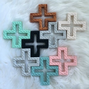 Geometrischer Kreuz Silikon Beißer mit Textur. Baby-Greifvogel aus Kupfer, grau, weiß, rosa, mint, Seefoam und grauem Marmor. BPA frei. Bild 3