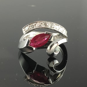 Op de afbeelding: Een zilveren ring met een marquise-vormige robijn en een band met kleine diamanten.