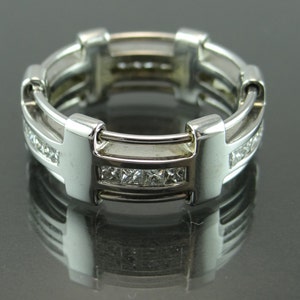May include: A silver ring with a multi-layered design and a row of small diamonds.