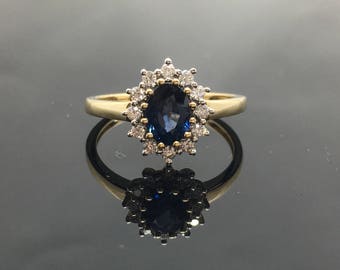 May include: A gold ring with a large oval blue sapphire surrounded by a halo of smaller diamonds.