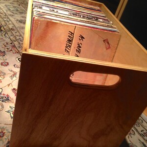 May include: A wooden crate filled with vinyl records. The crate has a cutout handle and the text "As Safe A Humble" is visible on the top of the crate.