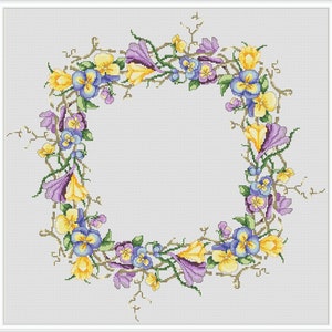 Op de afbeelding: Een krans van paarse en gele bloemen met groene bladeren op een witte achtergrond.