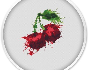 Puede incluir: Dos cerezas rojas con hojas y tallos verdes, pintadas en estilo acuarela con salpicaduras rojas y verdes sobre un fondo blanco.