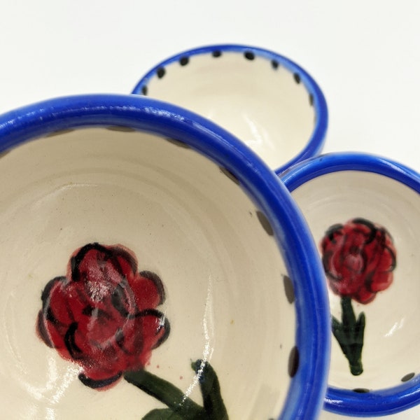 Tiny handmade ceramic white bowl with hand painted blue rim and red flower