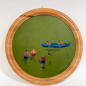 May include: A circular painting in a light wood frame featuring a solid olive green background. The artwork depicts a bright blue canoe with two figures paddling, and three other figures standing in the water below, all rendered in a loose style.
