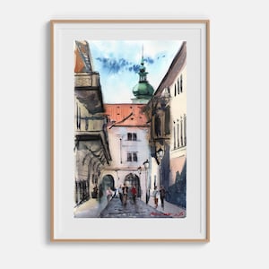 Könnte beinhalten: Ein gerahmtes Aquarellbild, das eine schmale europäische Straßenszene mit hohen Gebäuden, einem zentralen Bauwerk mit grüner Kuppel und mehreren Personen zeigt, die auf dem Kopfsteinpflaster unter einem blauen Himmel mit Wolken gehen.
