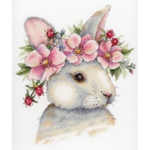 Könnte beinhalten: Kreuzstich-Design eines Hasen mit Blumenkranz. Der Hase ist hauptsächlich weiß und grau, mit rosa Akzenten auf den Ohren und Blumen. Der Kranz besteht aus rosa Blüten, grünen Blättern und roten Beeren. Der Hintergrund ist weiß.