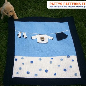 Puede incluir: Una manta de beb&eacute; hecha a mano con un dise&ntilde;o azul y blanco, con un tendedero con ropa de ganchillo en miniatura. La manta tiene un borde azul marino y est&aacute; decorada con aplicaciones de flores azules. El texto "PATTY'S PATTERNS ITALY" es visible.