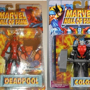 May include: Two action figures from the Marvel Hall of Fame series. The figures are Deadpool and Colossus. Deadpool is wearing a red and black suit and is holding two swords. Colossus is wearing a silver and red suit and is lifting a barbell.
