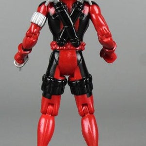May include: A red and black action figure of Deadpool with a black mask and a red and black suit. The figure is holding two swords in its back.