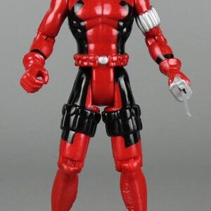 May include: A red and black action figure of Deadpool, a superhero with a mask, holding a silver sword. The figure has a black belt and black leg straps.