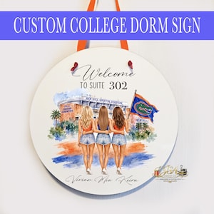 May include: A round white hanging sign featuring a watercolor illustration of three people standing with arms around each other in front of Ben Hill Griffin Stadium. The text reads Welcome TO SUITE 302, This is GATOR COUNTRY, and Vivian Mia Keira.
