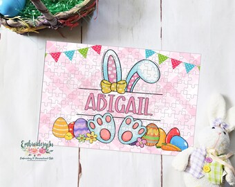 May include: A pink and blue Easter bunny puzzle with the name Abigail on it. The puzzle is surrounded by colorful Easter eggs and flowers.