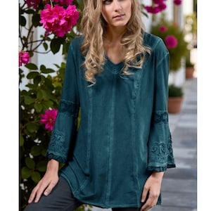 May include: A long-sleeved teal tunic featuring a V-neckline and flared sleeves with intricate tonal embroidery detailing. The garment has vertical seam stitching down the front and a relaxed fit, crafted from a solid-colored fabric.