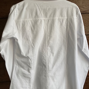 May include: A white long-sleeved button-down shirt with a classic collar and a slightly fitted silhouette.