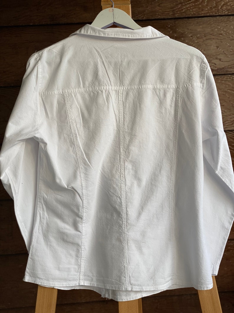 May include: A white long-sleeved button-down shirt with a classic collar and a slightly fitted silhouette.