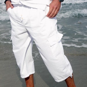 May include: White linen pants with a drawstring waist and cargo pockets. The pants are cropped and have a relaxed fit.