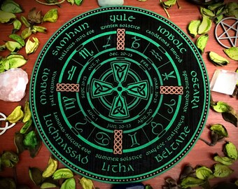 Op de afbeelding: Een zwart en groen cirkelvormig wiel met Keltische knopen en astrologische symbolen. Het wiel is verdeeld in acht secties, die elk een andere Sabbat vertegenwoordigen, een feestdag in Wicca-tradities. De Sabbats zijn Yule, Imbolc, Ostara, Beltane, Litha, Lammas, Mabon en Samhain. Het wiel bevat ook de data van de zonnewendes en equinoxen.