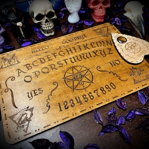 Könnte beinhalten: Holz-Ouija-Brett mit Planchette, Alphabet, Zahlen und den Wörtern "Hallo", "Lebwohl", "Ja" und "Nein".