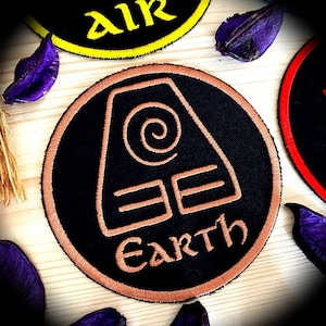 May include: A black and brown embroidered patch featuring the Earth symbol and the word "EARTH" in a stylised font.
