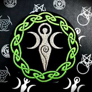 Puede incluir: Un diseño de nudo celta verde rodea una figura femenina estilizada blanca con tres lunas crecientes. El fondo es negro.