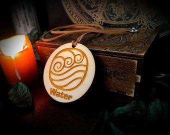 May include: A wooden pendant with a water symbol and the word "Water" engraved on it. The pendant is hanging from a brown leather cord.