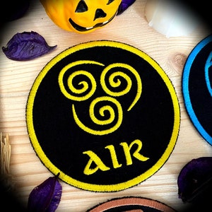 May include: A black and yellow embroidered patch featuring a stylised air symbol and the word "AIR" in yellow lettering.