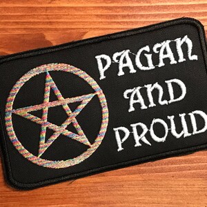 May include: Black patch with white embroidered text "Pagan and Proud" and a rainbow pentagram.