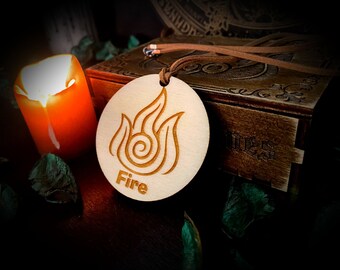 May include: A wooden pendant with a fire symbol and the word "Fire" engraved on it. The pendant is hanging from a brown leather cord.