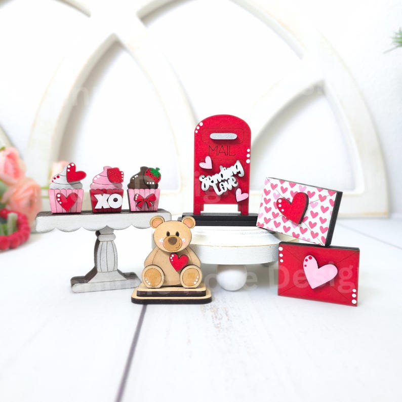 Pode incluir: Decora&ccedil;&otilde;es de madeira para o Dia dos Namorados, incluindo uma caixa de correio vermelha com as palavras "Sending Love", um urso de peluche a segurar um cora&ccedil;&atilde;o, cupcakes com cora&ccedil;&otilde;es e XO, e envelopes com cora&ccedil;&otilde;es.