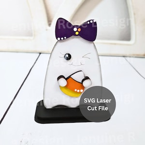 Può includere: Un fantasma bianco con un fiocco viola e un viso che strizza l'occhio tiene un mais dolce giallo e arancione. Il fantasma è in piedi su una base nera. Il testo "SVG Laser Cut File" è su un cerchio sullo sfondo.
