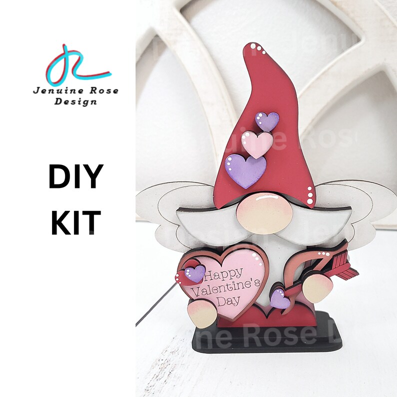 May include: A wooden DIY kit featuring a Valentine's Day gnome. The gnome has a red hat, a white beard, and a heart-shaped body with the text "Happy Valentine's Day." The kit includes a wooden base and decorative hearts.