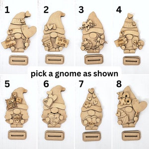 Puede incluir: Ocho adornos de gnomo de madera sin terminar con diferentes dise&ntilde;os tem&aacute;ticos de San Valent&iacute;n. Los gnomos sostienen corazones, letreros y otras decoraciones. Los gnomos est&aacute;n numerados del 1 al 8.