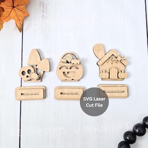 Könnte beinhalten: Drei Halloween-Holzausschnitte. Die Designs umfassen einen Totenkopf mit Pilzen, einen Kürbis-Korb und ein Spukhaus mit Kürbissen. Jeder Ausschnitt hat eine rechteckige Basis. Der Text "SVG Laser Cut File" ist sichtbar.