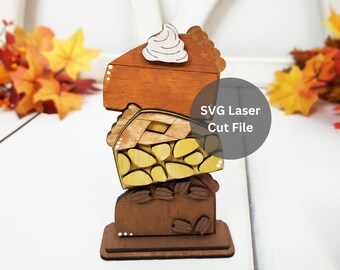 May include: A stack of three wooden pie slices, each with a different design and color. The top slice is a pumpkin pie with a dollop of whipped cream, the middle slice is an apple pie with a lattice crust, and the bottom slice is a chocolate pie with pecans. The slices are stacked on a wooden base. SVG Laser Cut File.