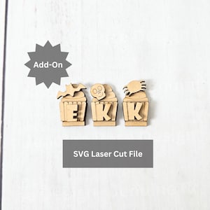 May include: Three laser-cut wooden cupcake-shaped decorations with Halloween-themed toppers: a bat, a skull, and a spider. Each cupcake has the letters "E", "K", and "K" on the front. The text "Add-On" and "SVG Laser Cut File" are also present.