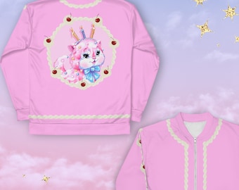 May include: Pink bomber jacket with a white zipper and white piping. The back of the jacket features a cartoon illustration of a pink and white cat with a blue bow, surrounded by cherries and candles.