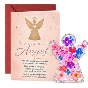 Op de afbeelding: Een wenskaart met een roze achtergrond, een gouden engelsilhouet en de tekst A GUARDIAN Angel, vergezeld door een doorzichtig engel-vormig ornament gevuld met geperste roze, paarse en blauwe bloemen, tegen een donkerrode envelop.