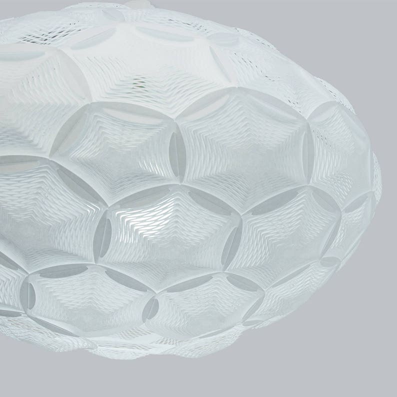 May include: White ceiling light fixture with a geometric, honeycomb-like design. The light fixture is made of a translucent material and has a rounded shape.