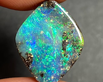 May include: A green, blue, and black opal gemstone with a diamond shape. The opal has a dark, black background with flashes of green and blue.