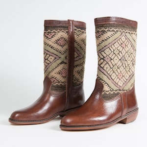 May include: A pair of brown leather boots with a geometric patterned fabric shaft. The boots have a pointed toe and a low heel.