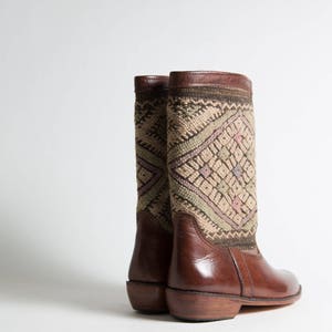 May include: A pair of brown leather boots with a patterned fabric shaft. The boots have a pointed toe and a low heel.
