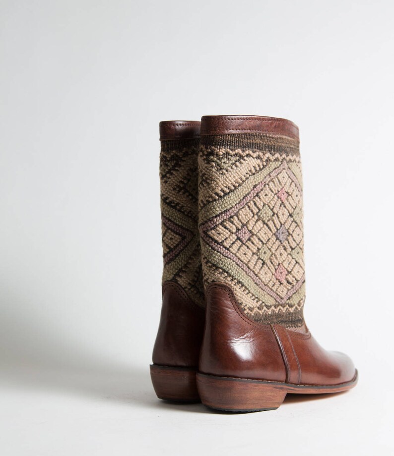 May include: A pair of brown leather boots with a patterned fabric shaft. The boots have a pointed toe and a low heel.